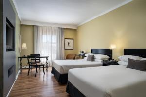 a hotel room with two beds and a desk at Protea Hotel by Marriott Bloemfontein in Bloemfontein