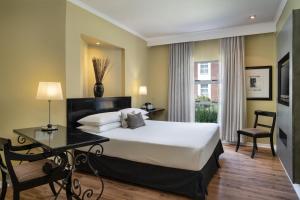 a hotel room with a bed and a desk and a window at Protea Hotel by Marriott Bloemfontein in Bloemfontein