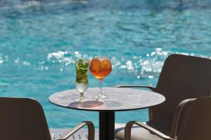 a table with two wine glasses on it next to the water at Atlantica Sungarden Park in Ayia Napa