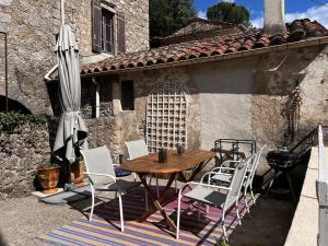 a table and chairs and an umbrella on a patio at La Pause Bleue in Saint-André-de-Majencoules