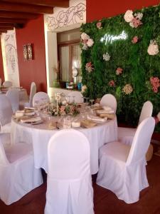 un tavolo con tavoli e sedie bianchi e fiori di Hotel Restaurante EL PATAS a Corral de Almaguer