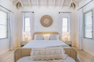 a bedroom with a large bed with white walls and windows at 118 Villa Aloe in Jolly Harbour