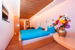 a bedroom with a blue bed with a vase of flowers at Haus Saler in Gaschurn