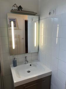 een witte badkamer met een wastafel en een spiegel bij Une Pause Chez Julien, appartement lumineux et idéalement situé! in Honfleur +17 foto's