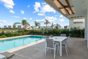 Un patio con mesa y sillas junto a una piscina. en Serenity Waves Villa 20, en Lárnaca