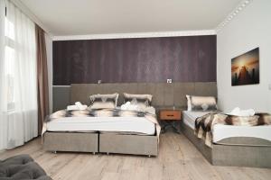 a bedroom with two beds and a purple wall at Kispet Deluxe Hotels&Suites in Oberhausen