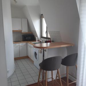 a small kitchen with a counter and two stools at Charmant studio in La Garenne-Colombes +6 photos