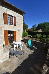 a patio with a table and chairs and a building at Gîte HAUTEROCHE BOISSON in Crançot