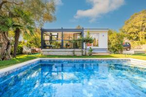 a swimming pool in front of a house at Jacaranda Cottage in Malinska
