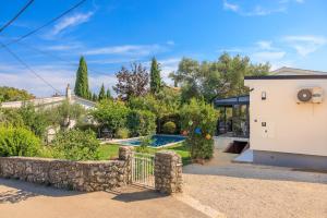 a house with a stone fence and a yard at Jacaranda Cottage in Malinska