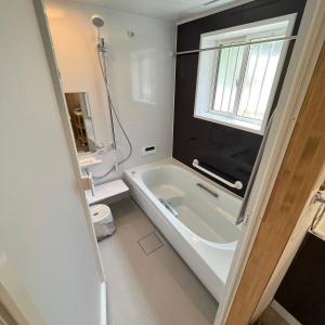 Un baño blanco con bañera y ventana. en Villa ANOTONA No 1, en Fujikawaguchiko