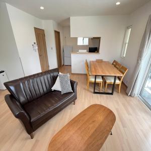 a living room with a leather couch and a table at Villa ANOTONA No 1 in Fujikawaguchiko