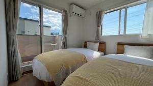 two beds in a room with two windows at Villa ANOTONA No 1 in Fujikawaguchiko