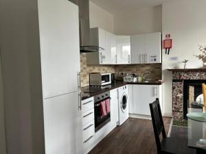 a kitchen with white cabinets and a washer and dryer at Sarsfield Hostel in Dublin