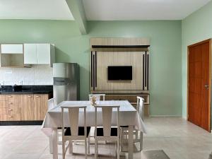 a kitchen with a table with chairs and a refrigerator at Residencial Leão 355 - Apartamentos econômicos - 15min a pé da Praia de Bombas in Bombinhas