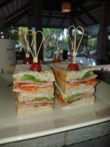 two sandwiches with toothpicks in them sitting on a plate at Monaburi Boutique Resort in Rawai Beach