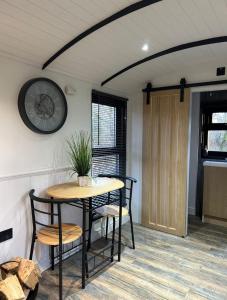 a table and chairs in a room with a clock on the wall at Flying Scotsman Unique Carriage Pet Friendly! Lazy Spa can be available upon request with additional cost of 40 in Bridgend +37 photos