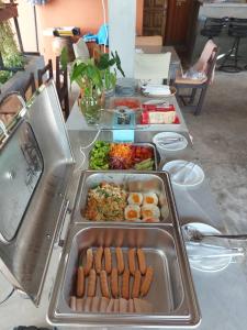 a table with several trays of food on it at Monaburi Boutique Resort in Rawai Beach
