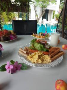 a table with two plates of breakfast food on it at Monaburi Boutique Resort in Rawai Beach