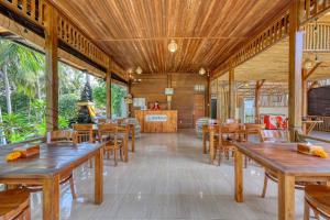 a dining room with wooden tables and chairs at Kelingking Tatakan Bungalow in Nusa Penida