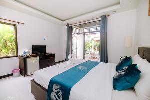 a bedroom with a large bed with blue pillows at Monaburi Boutique Resort in Rawai Beach