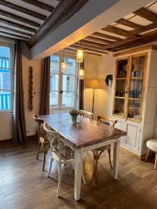 een eetkamer met een houten tafel en stoelen bij Une Pause Chez Julien, appartement lumineux et idéalement situé! in Honfleur