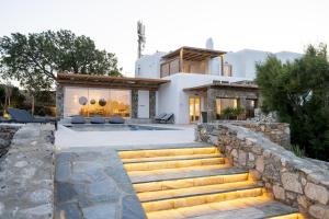 a house with a swimming pool and a stone wall at Ambiente Villas 3Βd-Agios Ioannis in Agios Ioannis Mykonos