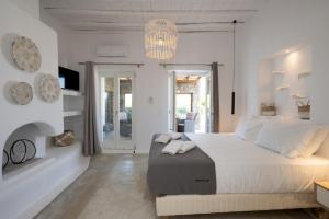 a white bedroom with a large bed and a chandelier at Ambiente Villas 3Βd-Agios Ioannis in Agios Ioannis Mykonos