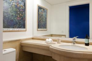 a bathroom with a sink and a painting on the wall at Safi Blues 3 BR Apartment in Beirut +24 photos