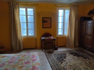una camera da letto con un letto, un tavolo e finestre di Comme chez vous "pour 4 personnes" a Puycornet
