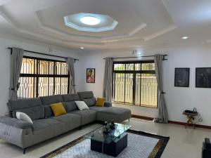 Una sala de estar con un sofá y dos ventanas. en Emmalanta Safaris House, en Arusha