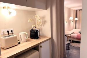 a kitchen with a counter with a toaster and a bedroom at Chambre d'hôtes option étape pour professionnel in Morangis