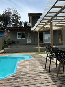 a wooden deck with a swimming pool and a pergola at Casa Mathia in Caraíva