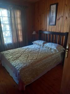 a bed in a bedroom with a wooden wall at Emerald Hill Cabin in Mount Pleasant