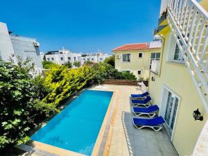 Una piscina con sillas al lado de un edificio. en Villa Daria, en Kyrenia
