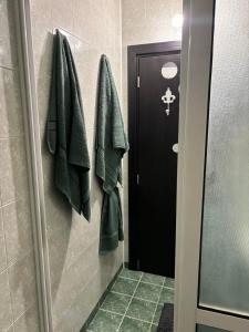 a bathroom with a black door and green towels at Апартамент 8 in Varna City