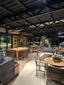 a restaurant with tables and ping pong tables at Celeiro Lake Village in São Francisco de Paula
