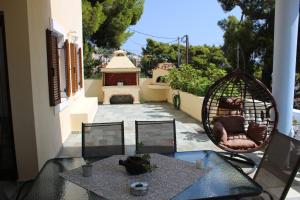a patio with a table and chairs and a swing at Eleni's Guest House in Patitiri