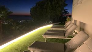 a row of lounge chairs on the side of a building at Bluehillsitges - Only Adults in Sitges +126 photos