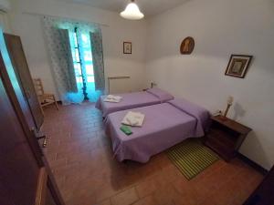 a bedroom with two beds with purple sheets at Podere Santa Giulia - casale Francianina in Piombino