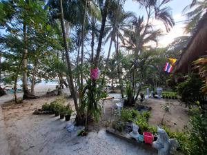 a beach with palm trees and chairs and flowers at Baan Suan Kayoo 1 Long beach Aow Yai in Ko Phayam