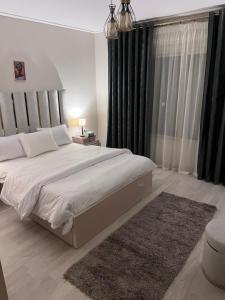 a bedroom with a large white bed with black curtains at A Luxury Hotel Appartment at NEW GIZA Imperial Compound قريبة جدا للمتحف المصري الجديد in Abū Rawwāsh
