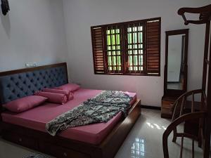 a bedroom with a bed with pink sheets and a window at Orkid villa in Hikkaduwa