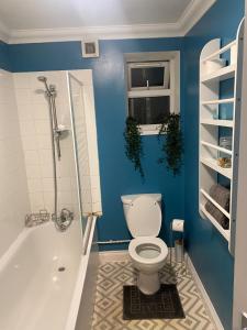 a blue bathroom with a toilet and a tub and a window at Sea Side Home from Home in Portsmouth