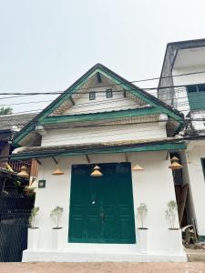 a green door on a white house with potted plants at Aloha LuangPrabang Hostel Capsule in Luang Prabang