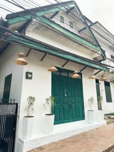 a green door on a white house with potted plants at Aloha LuangPrabang Hostel Capsule in Luang Prabang