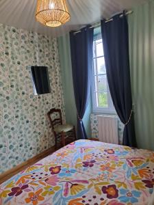 Un dormitorio con una cama con colcha floral y una ventana. en Gîte 4 pers avec option sauna- Classé 3 étoiles- Sud charente, en Lagarde-sur-le-Né 19 fotos más