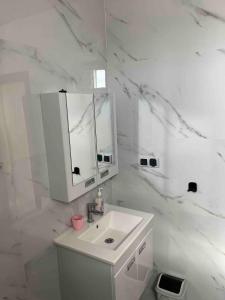 a white bathroom with a sink and a mirror at Dar Manzily in Draïd