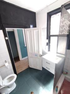 a bathroom with a toilet and a sink and a door at Hostal Perro Watón in Valparaíso +60 photos