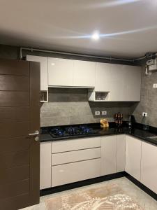 a kitchen with white cabinets and a stove top oven at شقة فندقية نيو جيزة الشيخ زايد in Abū Rawwāsh